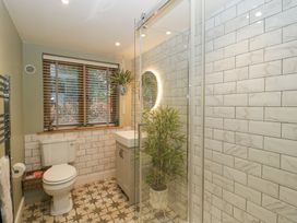 A bathroom with a toilet sink and glass shower enclosure with plants near the window at Pheasants Rise Apartment in Ross-On-Wye