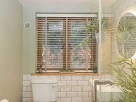 A bathroom with a toilet sink window blinds and green plants at Pheasants Rise Apartment in Ross-On-Wye