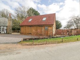 A wooden garage with two skylights next to a gravel driveway and a stone chimney at Pheasants Rise Apartment in Ross-On-Wye