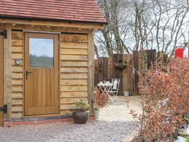 An outdoor area with a wooden door on a timber building a small white table with two chairs and potted plants at Pheasants Rise Apartment in Ross-On-Wye