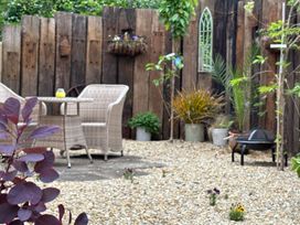 A garden with table and chairs surrounded by gravel and plants at Pheasants Rise Apartment in Ross-On-Wye