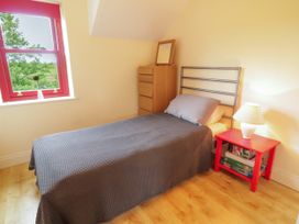 A bedroom with a bed, table, and lamp at Shane's Cottage in Falcarragh, County Donegal