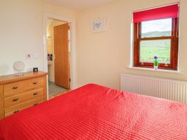 A bedroom with a red bedspread and a window in Shane's Cottage, Falcarragh, County Donegal