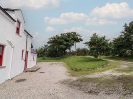 An outdoor view of a house with a gravel driveway and surrounding trees at Shane's Cottage in Falcarragh, County Donegal
