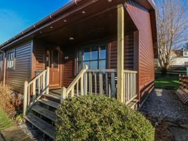 The exterior of a brown wooden cabin with a small porch and steps surrounded by bushes and grass at Creag Mhor Lodge in Back of Keppoch near Arisaig