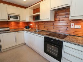 A kitchen with white cabinets a microwave sink toaster oven and electric stove at Creag Mhor Lodge Back of Keppoch near Arisaig