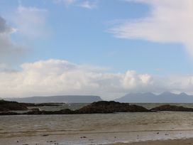 A coastal scene with rocky shorelines and distant mountains under a partly cloudy sky at Creag Mhor Lodge in Back of Keppoch near Arisaig
