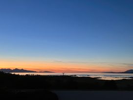 A coastal landscape at sunset with mountains in the distance and calm water at Creag Mhor Lodge Back of Keppoch near Arisaig