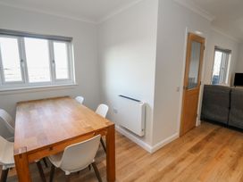 A dining area with a wooden table and white chairs next to windows and a room with a couch and a wooden door at Glen Mhor Lodge in Arisaig