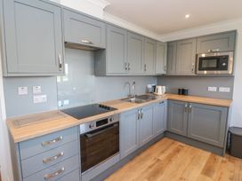 A kitchen with gray cabinets a built in oven a stovetop a microwave a sink a kettle and wooden countertops at Glen Mhor Lodge in Arisaig