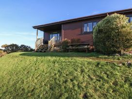 A wooden cabin with steps leading to a porch and a picnic table on grass at Glen Mhor Lodge in Arisaig