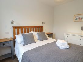 A bedroom with a bed with gray pillows and blanket two bedside tables and a white dresser at Glen Mhor Lodge in Arisaig