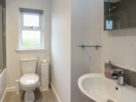 A bathroom with a toilet a sink a window and a glass shelf at Glen Mhor Lodge in Arisaig