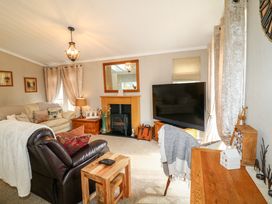 A living room with sofas and a TV beside a fireplace at The Lake House in Marston near Barkston