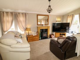 A living room with a cream sofa brown armchair fireplace and a large television at The Lake House in Marston near Barkston