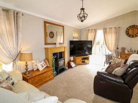 A living room with sofas a TV a fireplace and a wooden chest at The Lake House Marston near Barkston