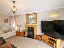 A living room with sofas a fireplace a large television and a wooden cabinet at The Lake House in Marston near Barkston