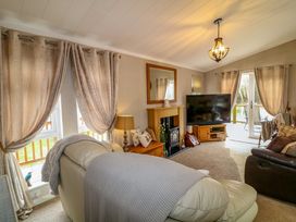 A living room with armchairs a fireplace a television and curtains at The Lake House in Marston near Barkston