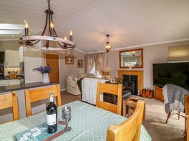 A living room with wooden dining chairs table covered with a green polka dot tablecloth and a fireplace at The Lake House in Marston near Barkston
