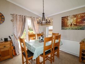 A dining room with a wooden table and six chairs and curtains on the window at The Lake House in Marston near Barkston
