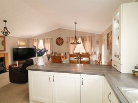 A living room and dining area with a dining table and chairs a television and a countertop with a vase of flowers at The Lake House in Marston near Barkston