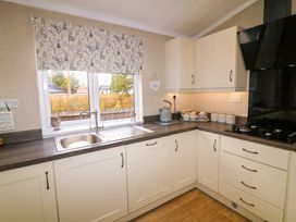 A kitchen with a sink under the window and cabinets and a stove at The Lake House in Marston near Barkston