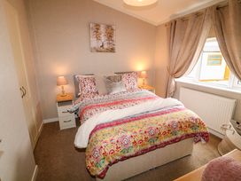A bedroom with a bed with patterned bedding two bedside tables with lamps and a window with curtains at The Lake House Marston near Barkston