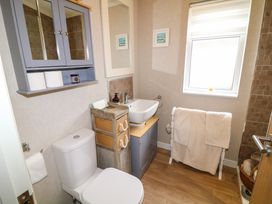 A bathroom with a toilet sink cabinet towel rack and window at The Lake House in Marston near Barkston