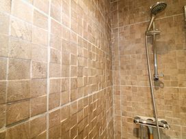 A shower area with beige tiled walls and a silver showerhead and control at The Lake House in Marston near Barkston