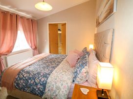 A bedroom with a bed floral bedding nightstand with a lamp and curtains on the window at The Lake House in Marston near Barkston