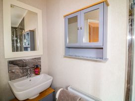 A bathroom with a sink a mirror a wall cabinet and a towel rack with a towel at The Lake House in Marston near Barkston