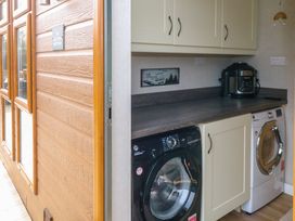 A utility room with a black washing machine a white dryer and cream cabinets at The Lake House Marston near Barkston