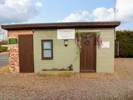 A small building with two brown doors and a window with flower decorations and signs on the wall at The Lake House in Marston near Barkston