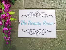 A sign on a textured wall that reads The Beauty Room with flowers on the side at The Lake House in Marston near Barkston