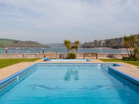 An outdoor area with a swimming pool and a view of water and boats at 43 The Salcombe Salcombe