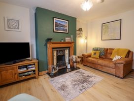 A living room with a brown leather sofa pillows a fireplace and a wooden TV stand at Gwynfa in Ysbyty Ifan