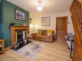 A living room with a fireplace a brown leather sofa and a wooden staircase at Gwynfa in Ysbyty Ifan