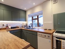 A kitchen with wooden countertops green cabinets a sink a stove and a window showing an outdoor view at Gwynfa in Ysbyty Ifan
