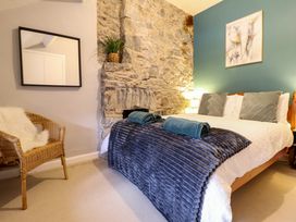A bedroom with a bed towels on a blanket a chair with a cushion and a mirror on the wall at Gwynfa in Ysbyty Ifan