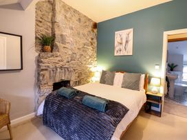 A bedroom with a bed and blankets near a stone wall and a painting of elephants at Gwynfa in Ysbyty Ifan
