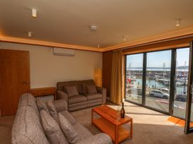 A living room with two sofas a wooden coffee table and large windows overlooking a marina at Apartment 1 in Scarborough