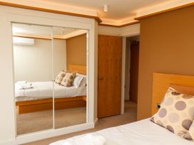 A bedroom with a bed topped with polka dot pillows a wooden door and a mirrored wardrobe at Apartment 1 in Scarborough