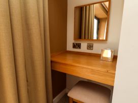 A wooden vanity desk with a square mirror a tissue box and a cushioned stool at Apartment 1 in Scarborough