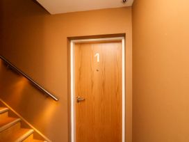 A stairway next to a wooden door with the number 1 on it at Apartment 1 in Scarborough
