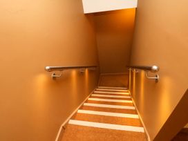 A stairway with brown walls carpeted steps and metal handrails on both sides at Apartment 1 in Scarborough