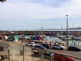 A harbor with boats docked and people walking near food stalls and parked cars at Apartment 1 in Scarborough