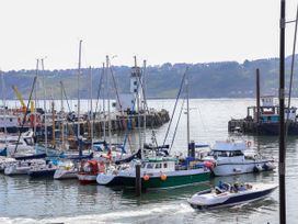 A harbor with several sailboats and motorboats docked and a speedboat with people on the water at Apartment 1 in Scarborough