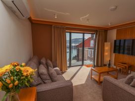 A living room with two sofas a coffee table a TV on the wall and a bouquet of yellow flowers at Apartment 2 in Scarborough