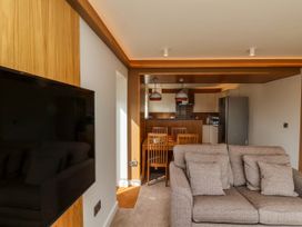 A living room with a sofa and a wall-mounted TV next to a dining area and kitchen at Apartment 2 in Scarborough
