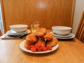 A dining table with croissants and raspberries on a plate with bowls and glasses of orange juice at Apartment 2 in Scarborough